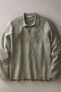 A long-sleeve knit polo shirt in a muted sage green color, featuring subtle horizontal textured stripes and a two-button placket, laid flat against a neutral gray background.