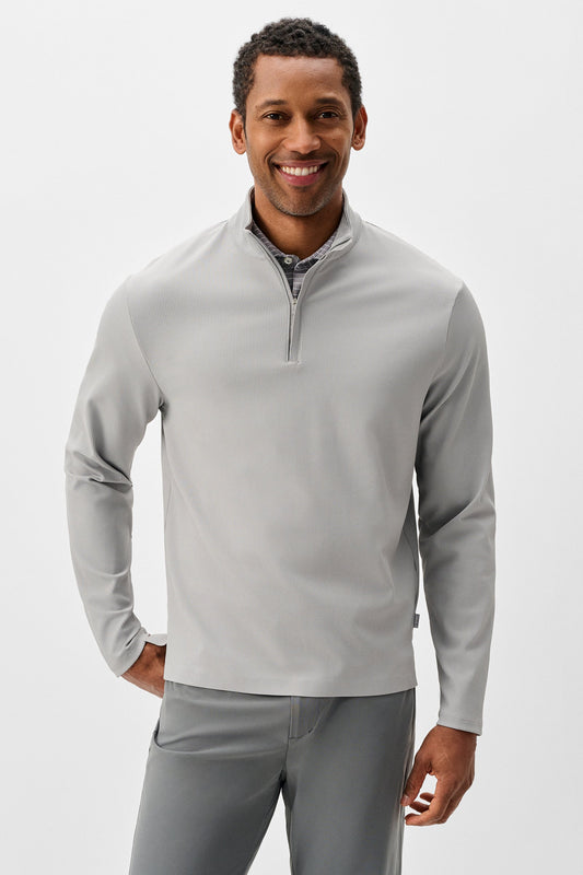 Man wearing a gray quarter-zip pullover and pants on a white background