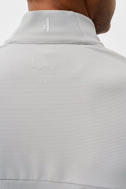 Close-up of a light gray ribbed knit sweater with a brand logo on a white background