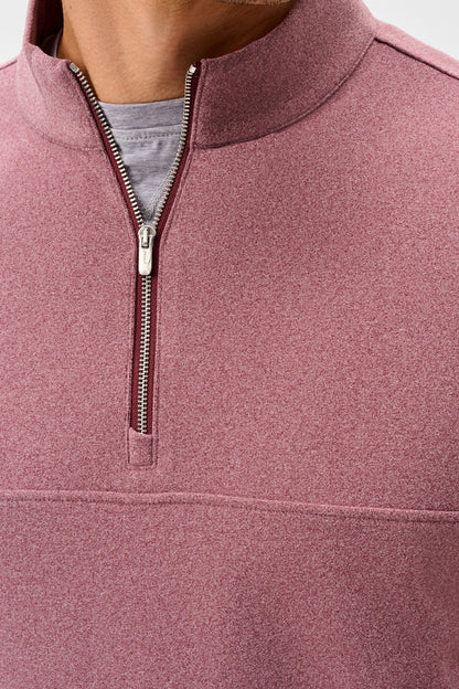 Close-up of a person wearing a heathered dusty rose quarter-zip pullover with a stand collar, showing the zipper, inner gray shirt, and fabric texture.