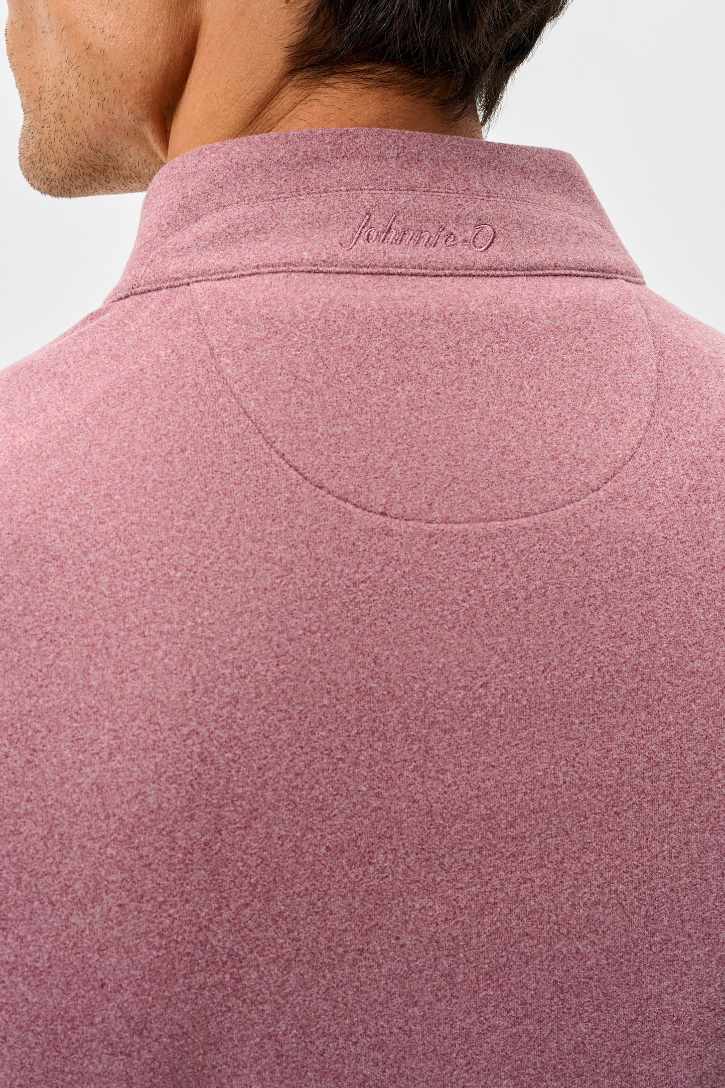 Close-up back view of a man wearing a dusty rose heathered quarter-zip pullover sweater with an embroidered 'Adrian D' logo on the collar, set against a plain light gray background.