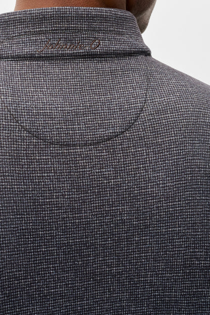 Close-up back view of a person wearing a dark gray textured knit polo shirt with a collar and subtle script embroidery inside the collar.