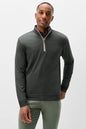 A man wearing a dark gray quarter-zip pullover sweater with a white zipper pull and a patterned shirt collar, paired with olive green pants, against a light gray studio background.