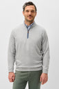Man wearing a gray quarter-zip sweater and green pants on a light gray background