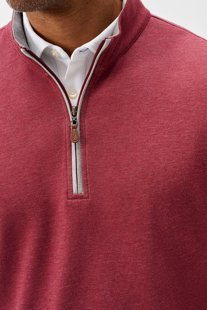 A close-up of a man wearing a heathered burgundy quarter-zip pullover sweater over a white collared shirt. The sweater features a mock neck, a silver zipper with a brown leather pull tab, and a white inner placket.