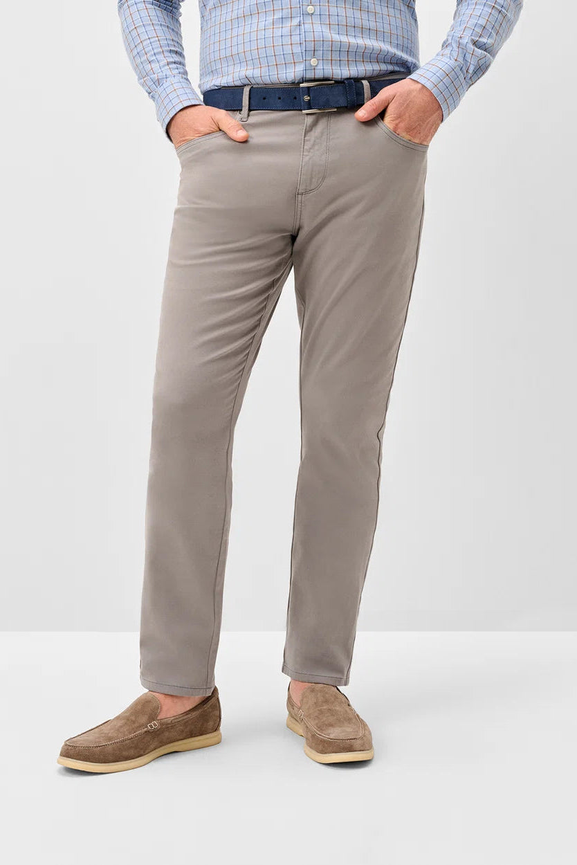 A man wearing slim-fit taupe trousers, a blue checkered shirt, a dark blue belt, and brown suede loafers, standing against a light gray studio background.