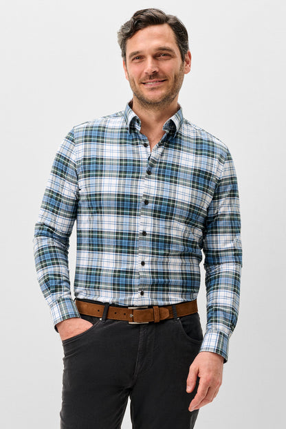 A man wearing a long-sleeve button-down plaid shirt in blue, white, and green, paired with black trousers and a brown belt, standing against a light gray background.