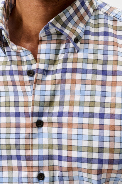 Close-up of a man wearing a long-sleeve button-down shirt with a multicolor plaid pattern in blue, green, orange, and white.