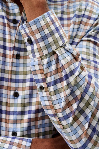 Close-up of a man wearing a long-sleeve plaid button-down shirt with a blue, brown, and white checkered pattern.