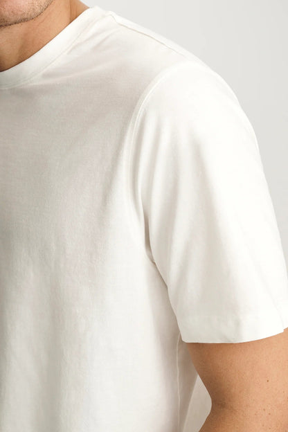Close-up of a person wearing a plain white t-shirt against a light gray background