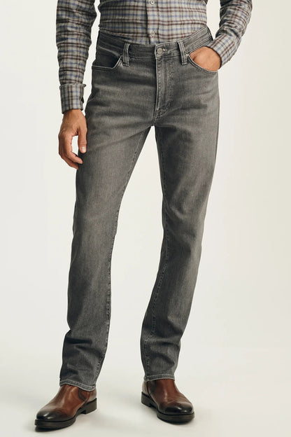 A person wearing slim-fit gray denim jeans with a plaid button-down shirt and brown leather shoes, shown from the waist down against a plain light background.