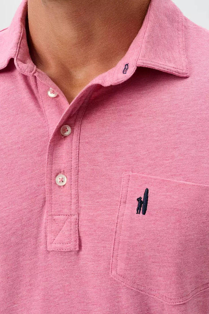 A close-up of a man wearing a pink heathered polo shirt with a chest pocket featuring a small black embroidered logo.