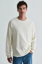 man in white long sleeve top in jeans