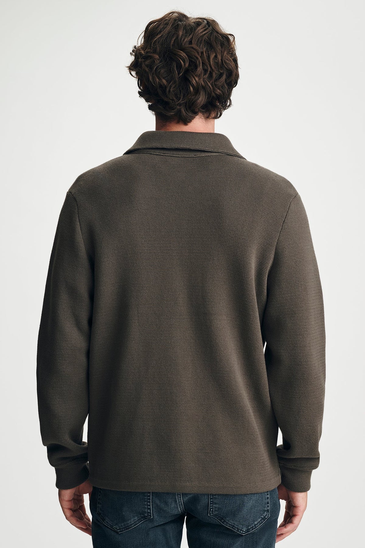 back view of man in brown sweater in jeans
