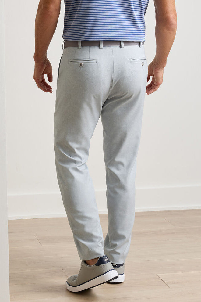 Person wearing light gray pants and a striped shirt on a plain background