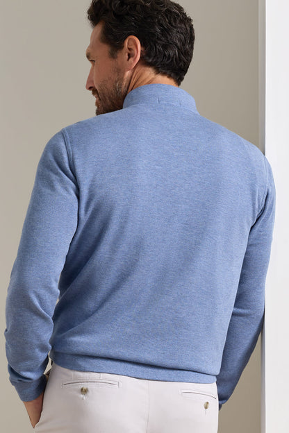 A man wearing a heathered blue long-sleeve knit sweater, shown from the back, paired with off-white trousers.