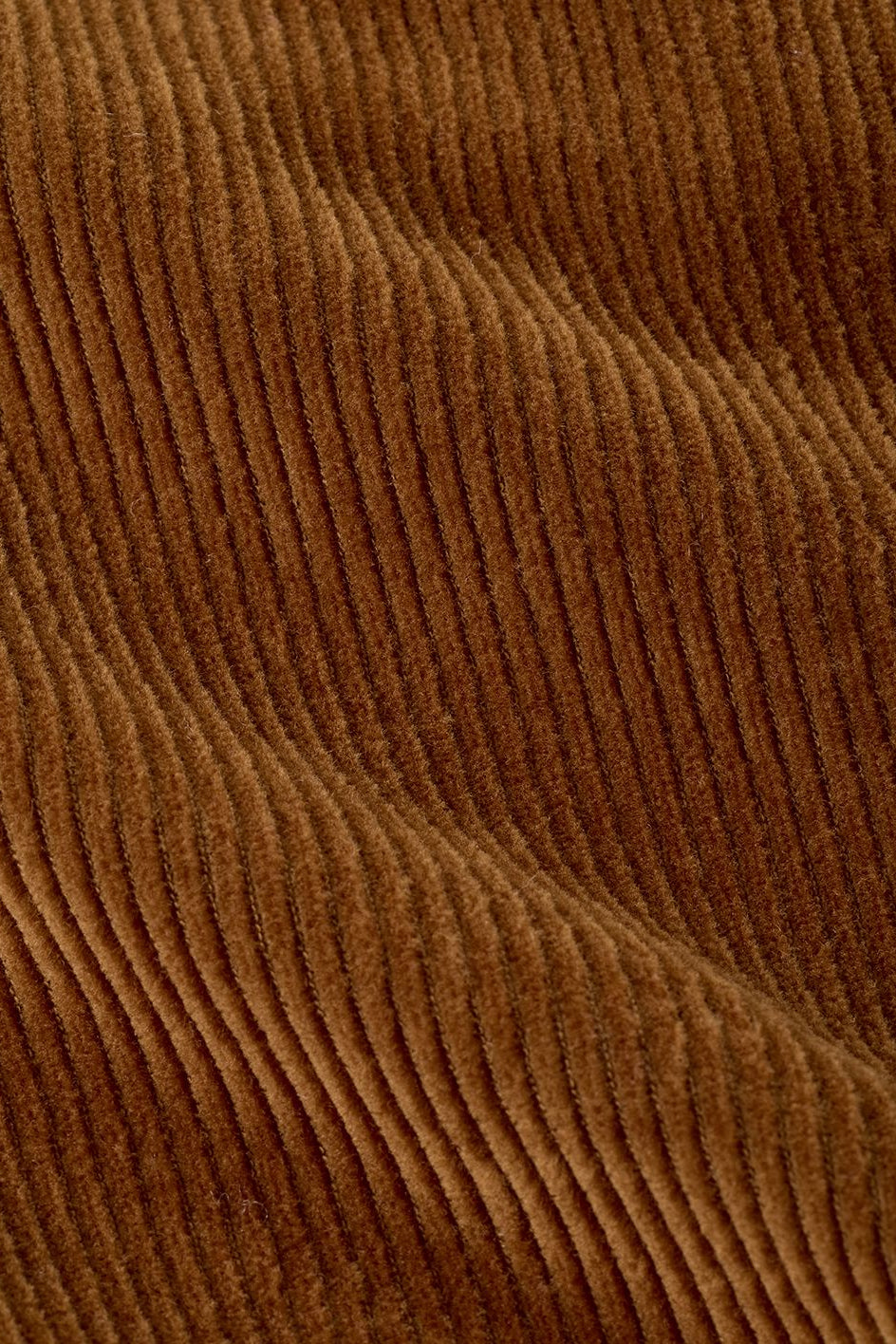 A close-up of a brown corduroy fabric showing the characteristic vertical ribbed texture and soft sheen.