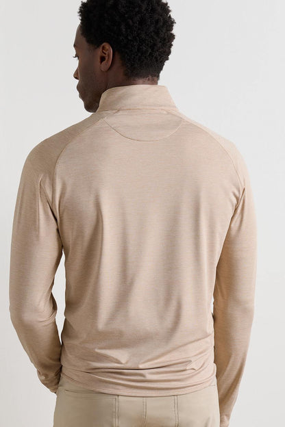 A man viewed from the back wearing a light beige long-sleeve mock neck athletic top and matching pants against a plain light gray studio background.