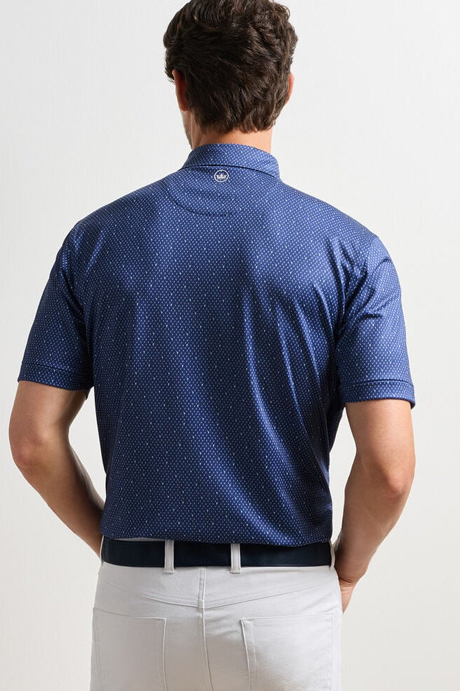 Man wearing a blue patterned polo shirt on a plain background