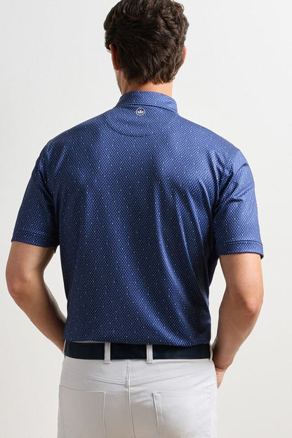 Man wearing a blue patterned polo shirt on a plain background