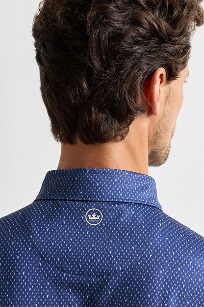Man wearing a blue patterned shirt with a visible brand logo on a light gray background