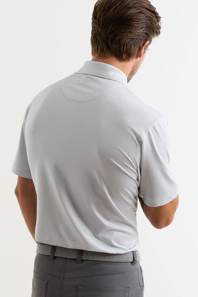 Man wearing a light gray polo shirt and dark gray pants on a white background