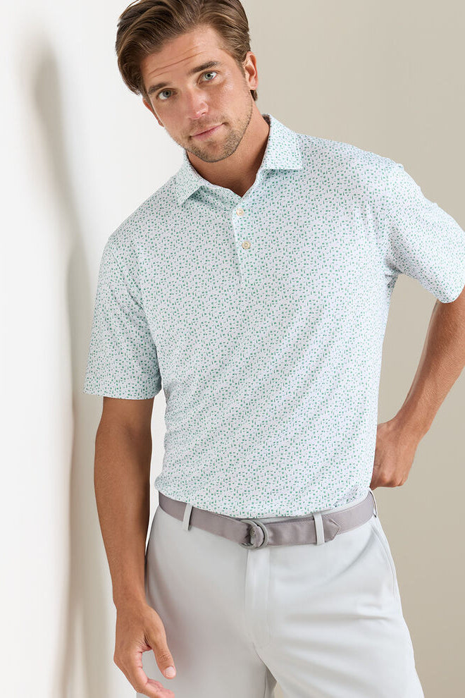 Man wearing a light blue patterned polo shirt and light gray pants against a beige background