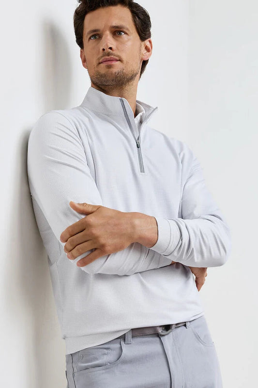 Man wearing a light gray quarter-zip sweater against a white background