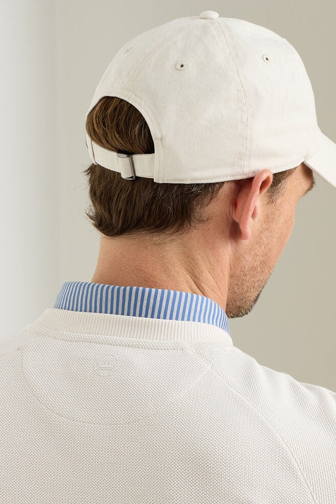 Man wearing a white cap and light-colored shirt against a plain background
