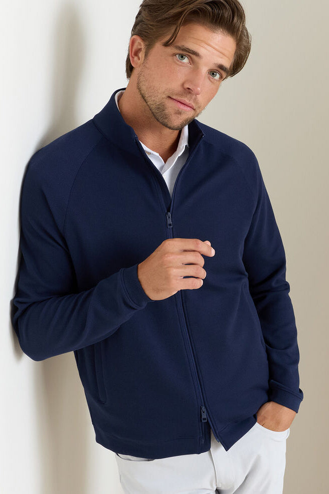 Man wearing a navy blue jacket against a neutral background