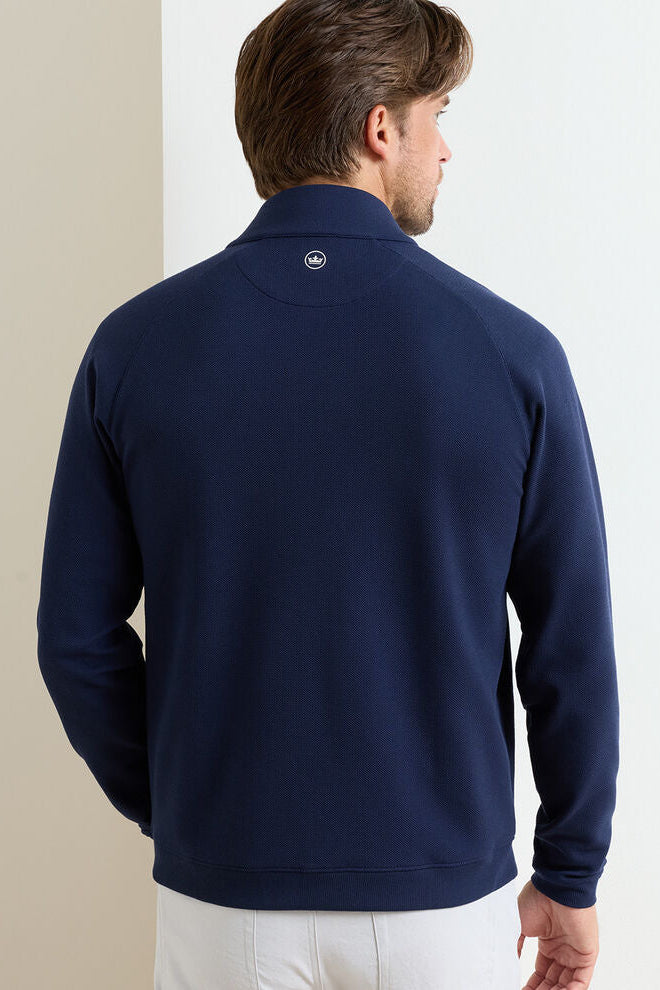 Man wearing a navy blue pullover with a visible brand logo on the chest.