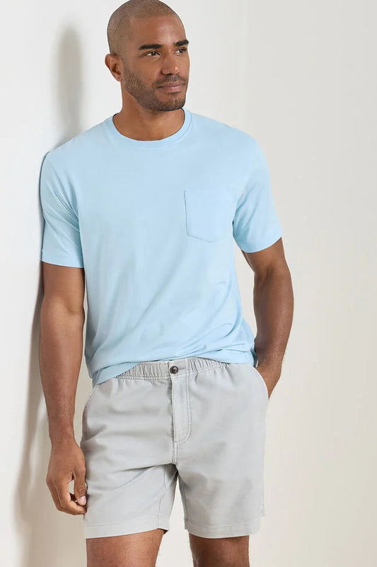 Man wearing a light blue t-shirt and gray shorts against a plain background