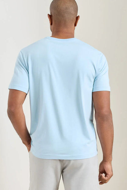 Man wearing a light blue t-shirt against a beige background