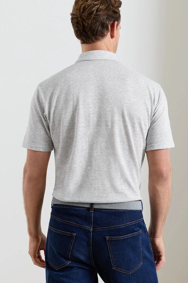 Man wearing a gray polo shirt and blue jeans against a plain background