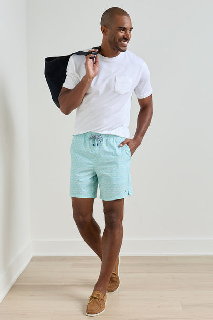 Man wearing a white t-shirt and light blue striped shorts holding a black bag.