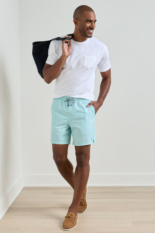 Man wearing a white t-shirt and light blue striped shorts holding a black bag.