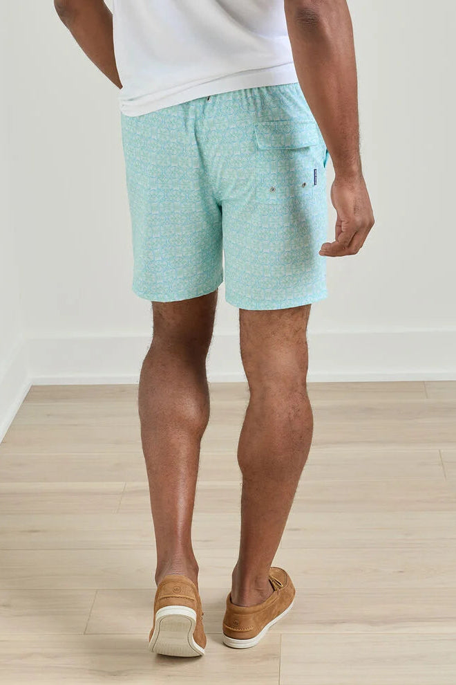 Person wearing light blue shorts and brown shoes on a wooden floor.
