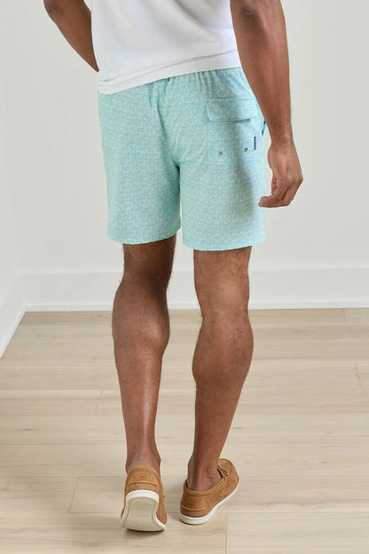 Person wearing light blue shorts and brown shoes on a wooden floor.