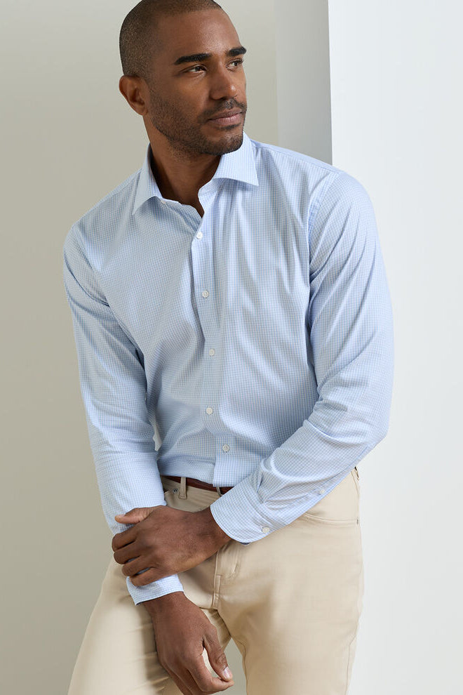 Man wearing a light blue shirt and beige pants against a plain background