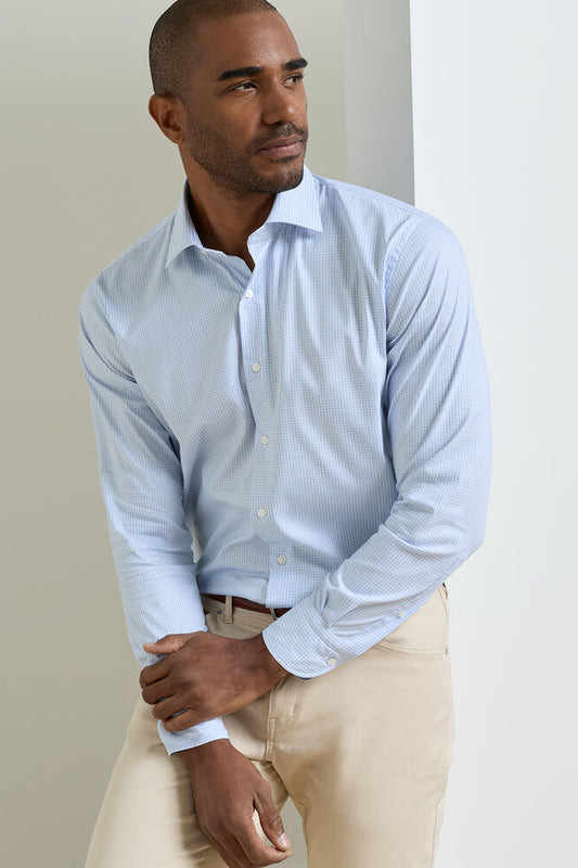 Man wearing a light blue shirt and beige pants against a plain background