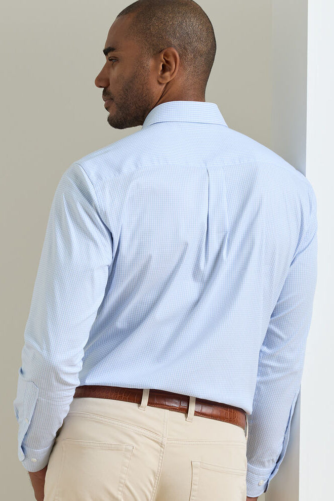 Man wearing a light blue checkered shirt and beige pants against a plain background