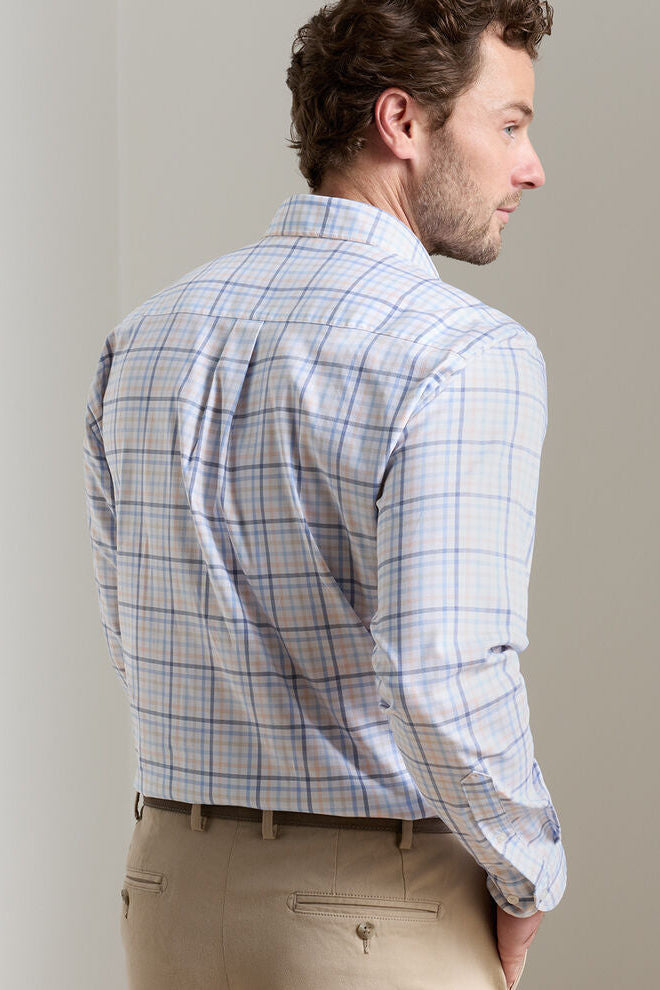 Man wearing a plaid shirt and beige pants against a plain background