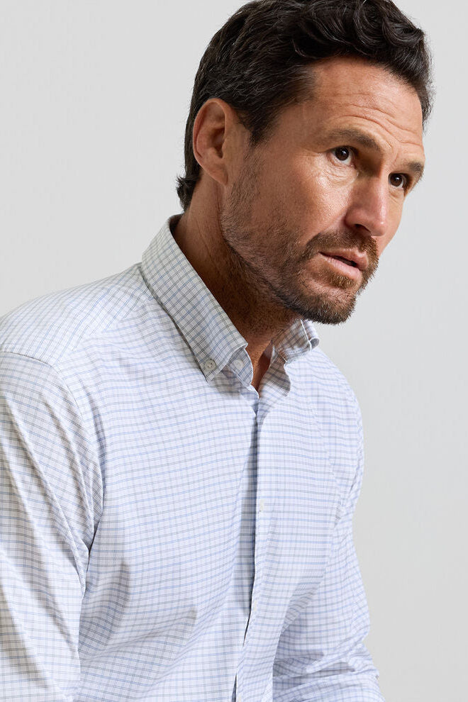 Man wearing a light blue checkered shirt against a plain background