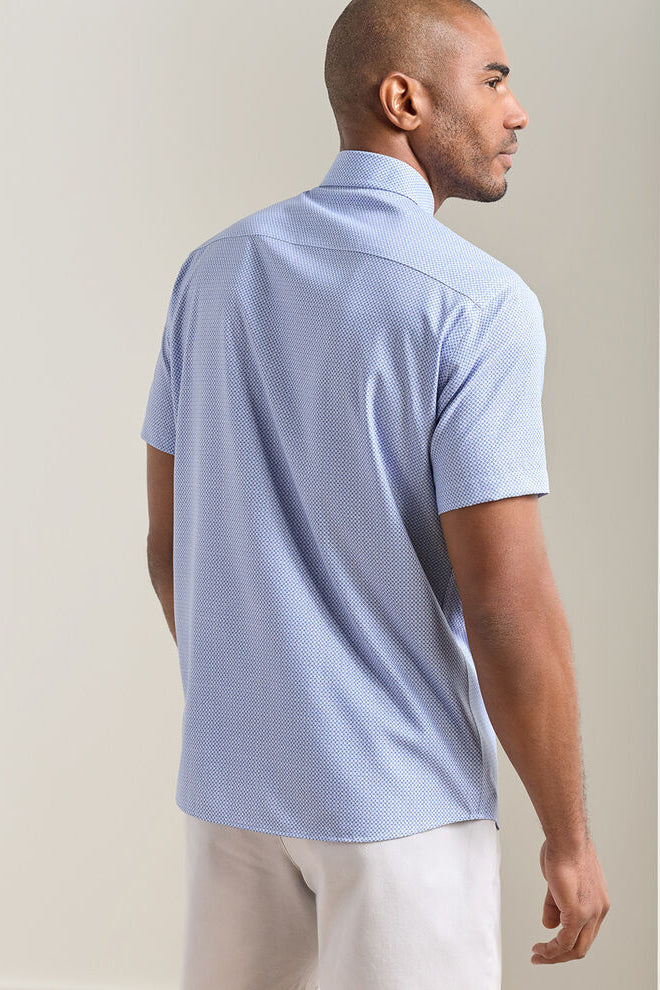 Man wearing a light blue patterned polo shirt against a beige background