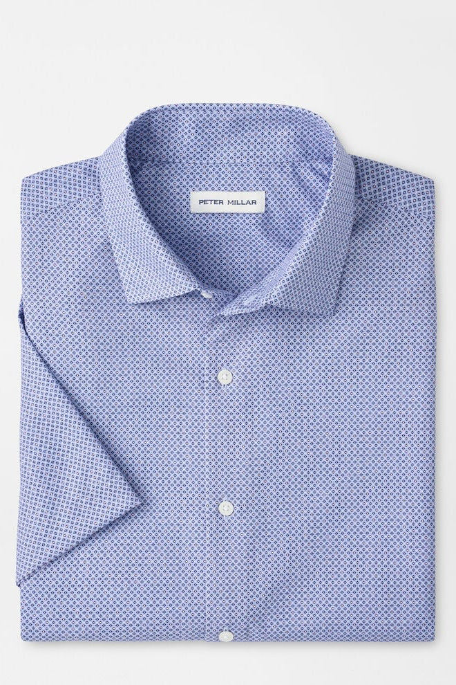 Folded blue patterned shirt with 'Peter Millar' label on a light gray background