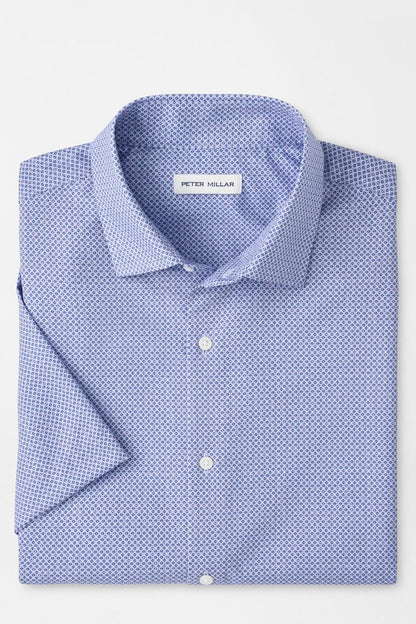 Folded blue patterned shirt with 'Peter Millar' label on a light gray background