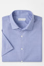 Folded blue patterned shirt with 'Peter Millar' label on a light gray background