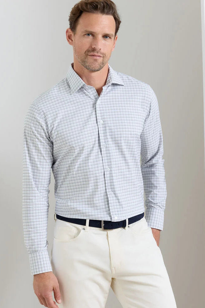 Man wearing a checkered shirt and white pants against a plain background