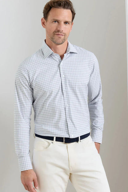 Man wearing a checkered shirt and white pants against a plain background