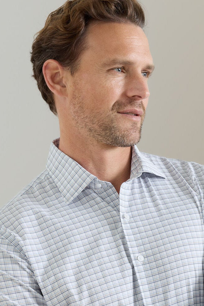 Man wearing a light gray checkered shirt against a neutral background